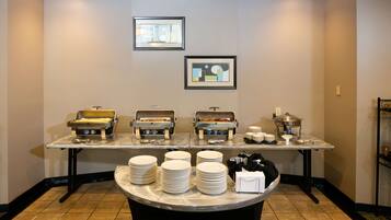 A buffet setup with multiple food stations, plates, and serving utensils.
