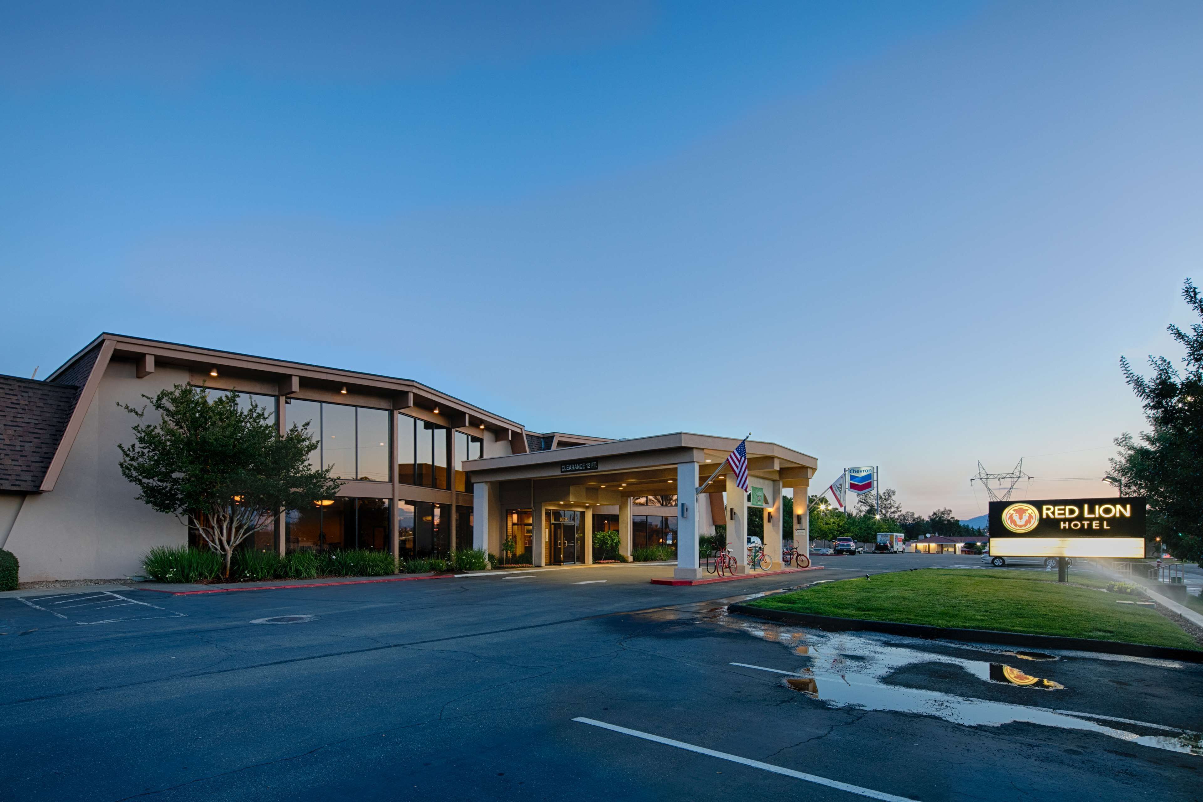 A Red Lion Hotel with a covered entrance, a parking lot, and a grassy area.