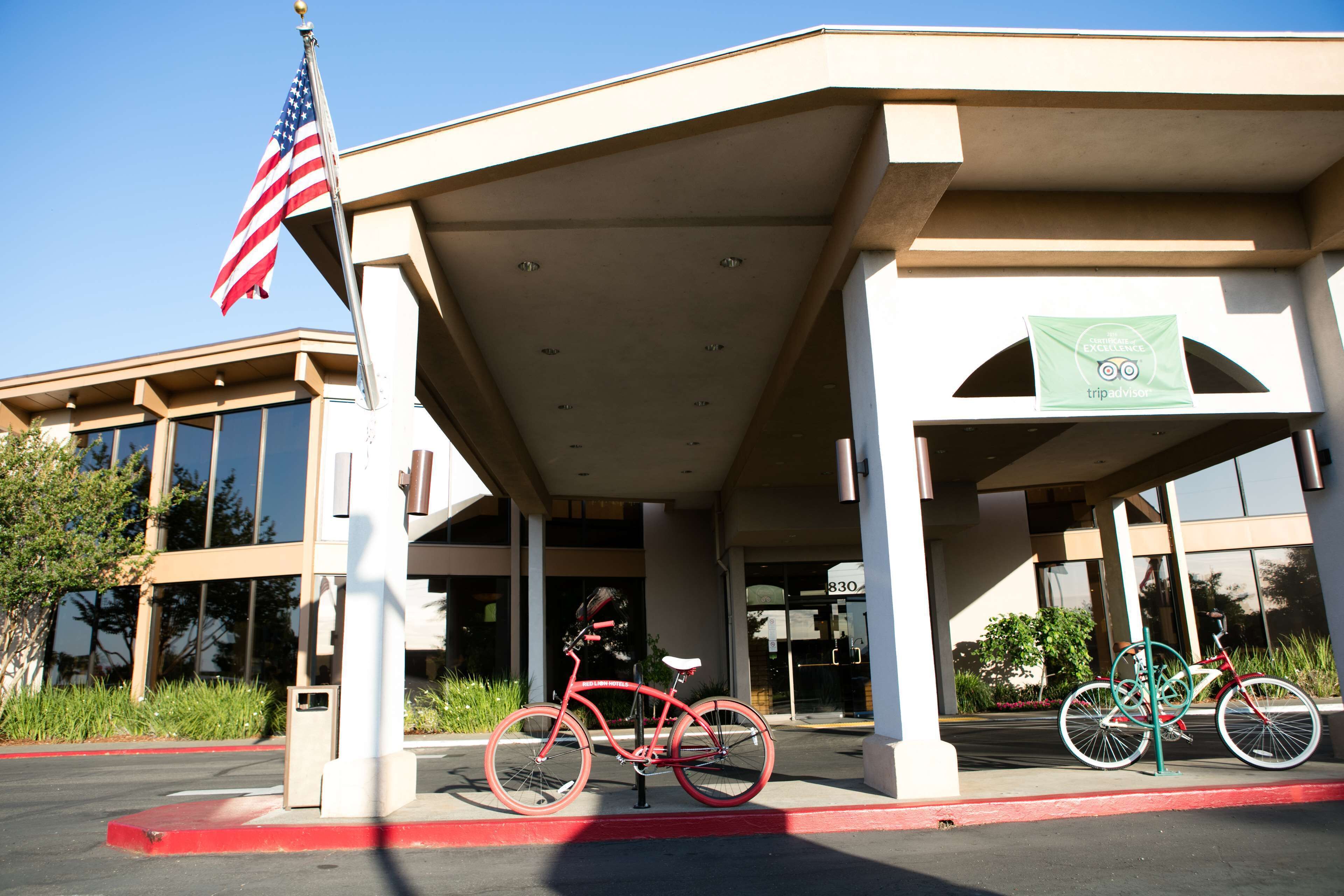 A building with a covered entrance, an American flag, and two bicycles parked outside.