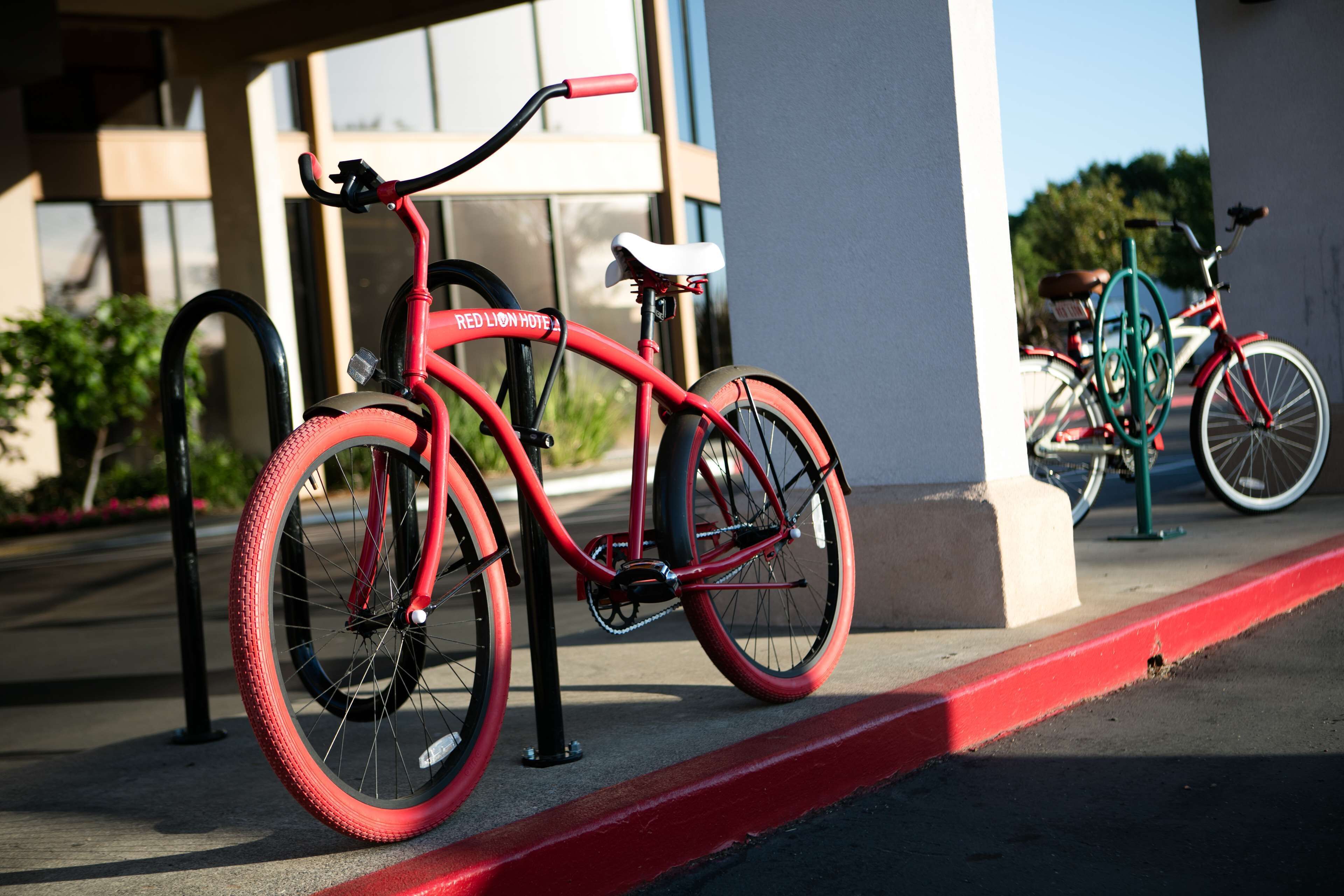 Una bicicleta roja estacionada frente a un edificio con bordillo rojo.