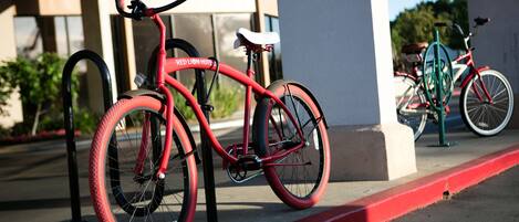 Una bicicleta roja estacionada frente a un edificio con bordillo rojo.