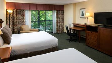 A hotel room with two beds, a desk, a television, and a chair.