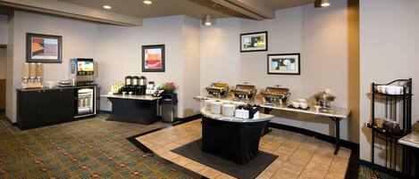 A hotel lobby with a reception desk, coffee station, and buffet area.