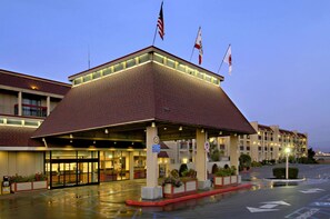 A hotel with a covered entrance, multiple flags, and a parking lot. - Red Lion Hotel Eureka (Eureka)