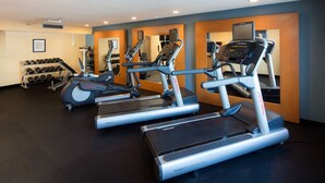 Un gimnasio con cintas de correr, mancuernas y discos de pesas.