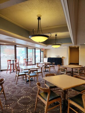 A restaurant with wooden tables and chairs, a patterned carpet, and hanging pendant lights. - Red Lion Hotel Eureka (Eureka)
