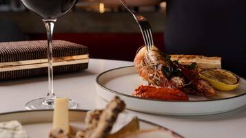 A dining table with a plate of food, a glass of drink, and a fork.