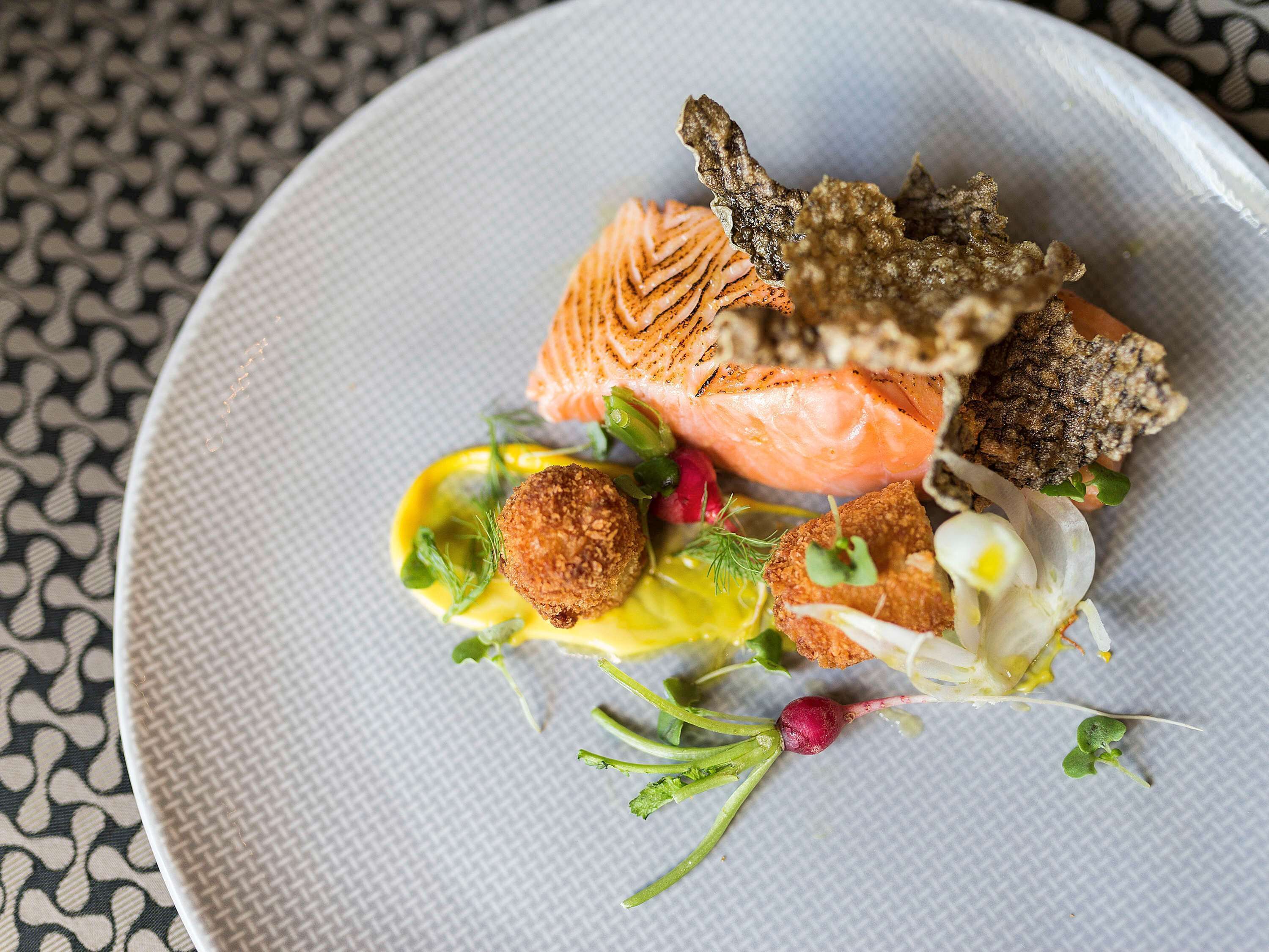 Ein Teller mit Lachs, panierten Speisen und Salat.