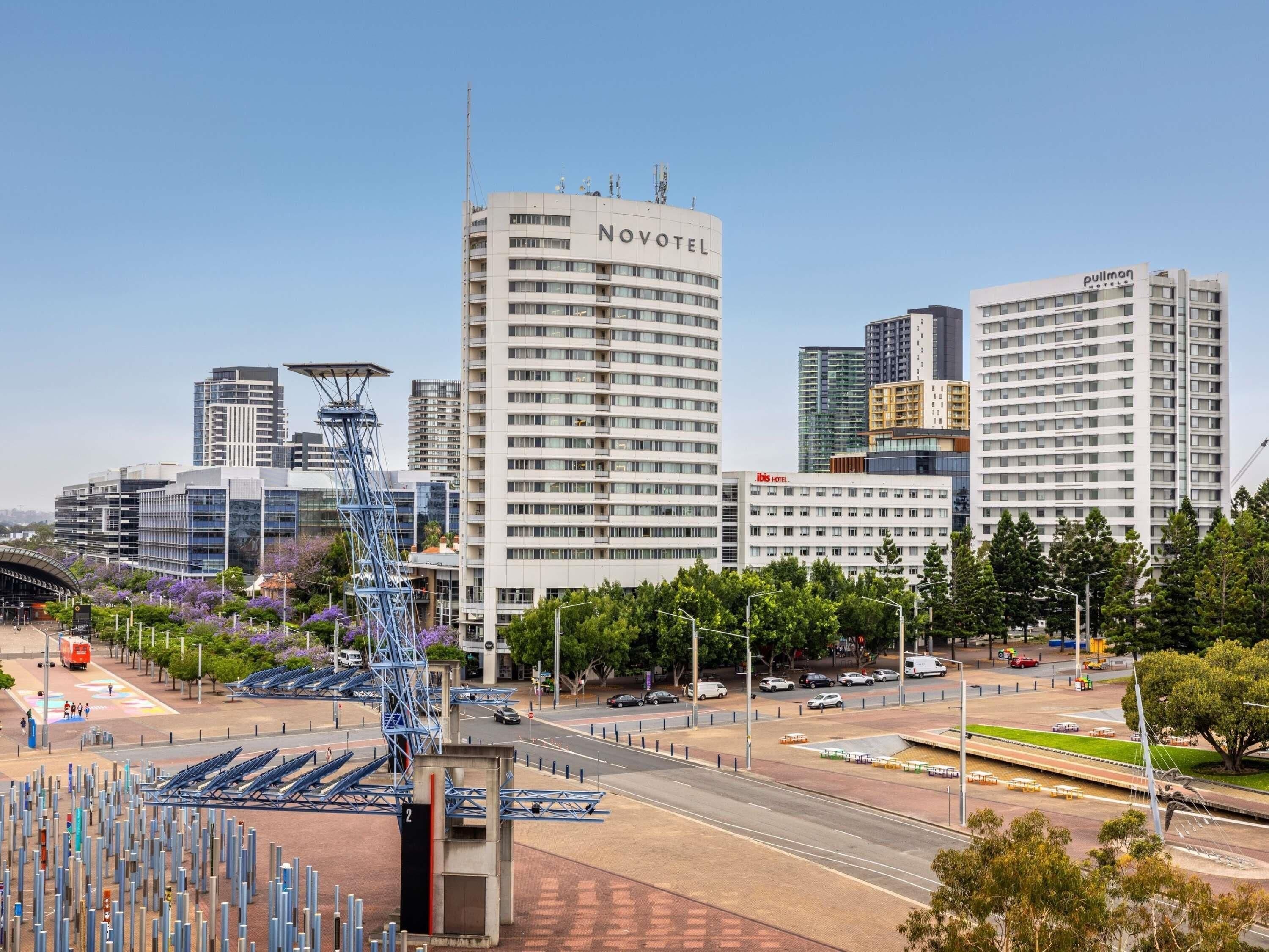 A Novotel hotel with a modern design, surrounded by other buildings and a busy street.