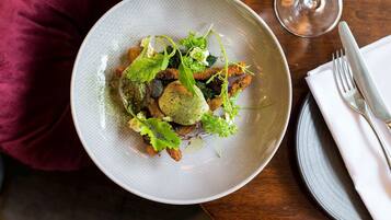 A plate of food on a table with a glass of white wine and a fork.