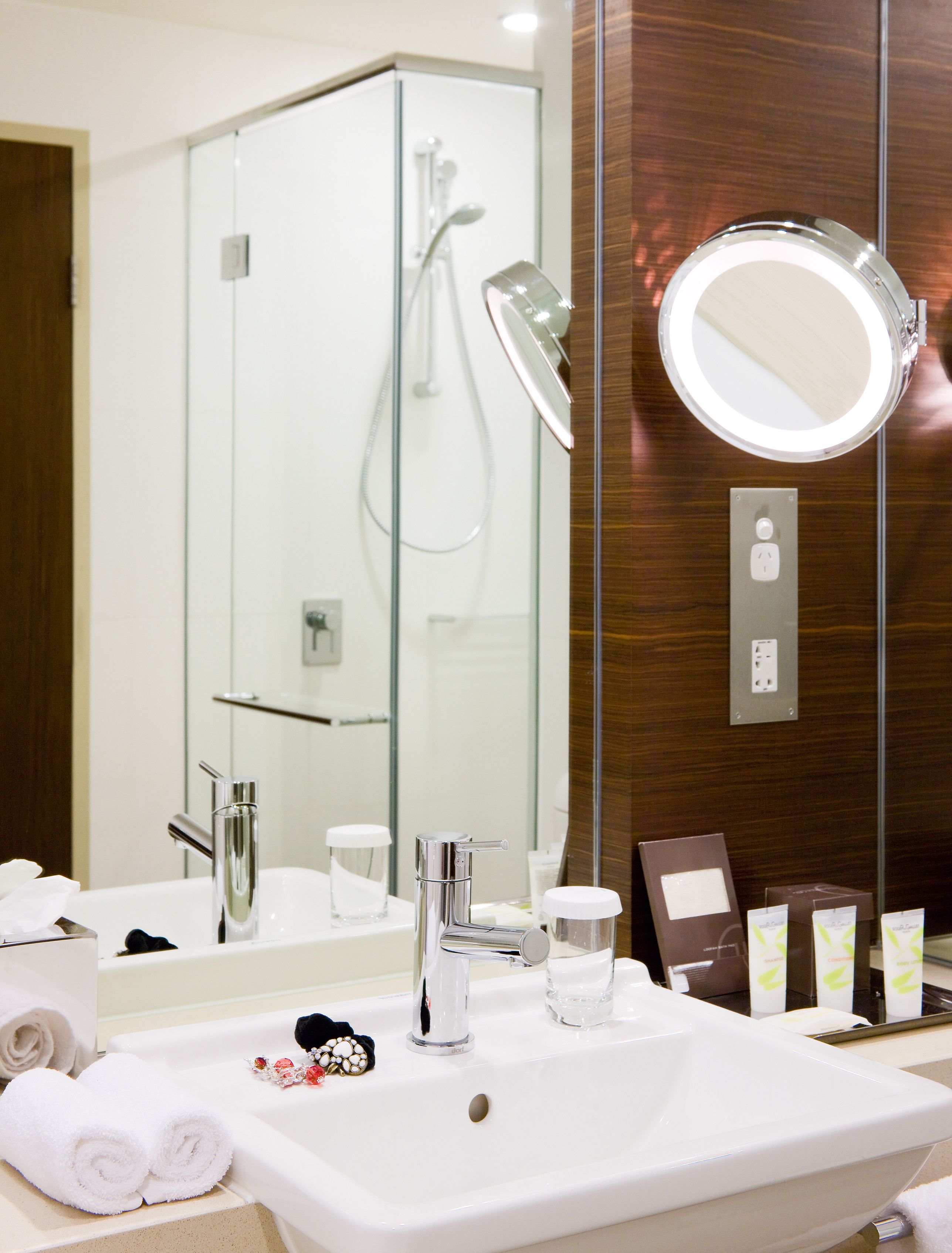 A modern bathroom with a large mirror, a sink, and a shower.