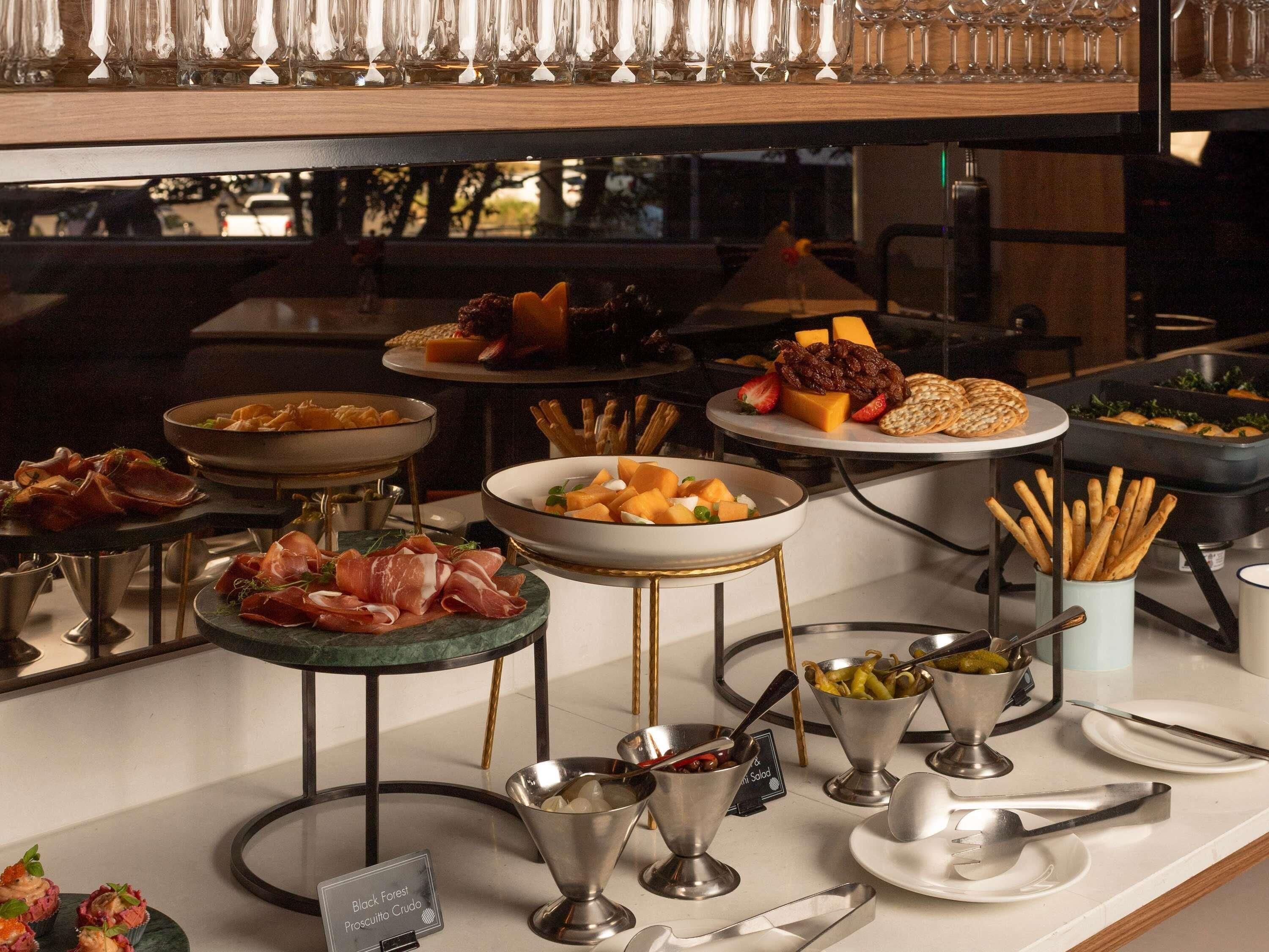 A buffet with various food items including meats, cheeses, and fruits.