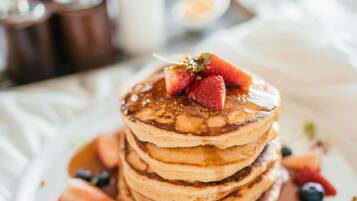 A stack of pancakes with strawberries and blueberries on a white plate.