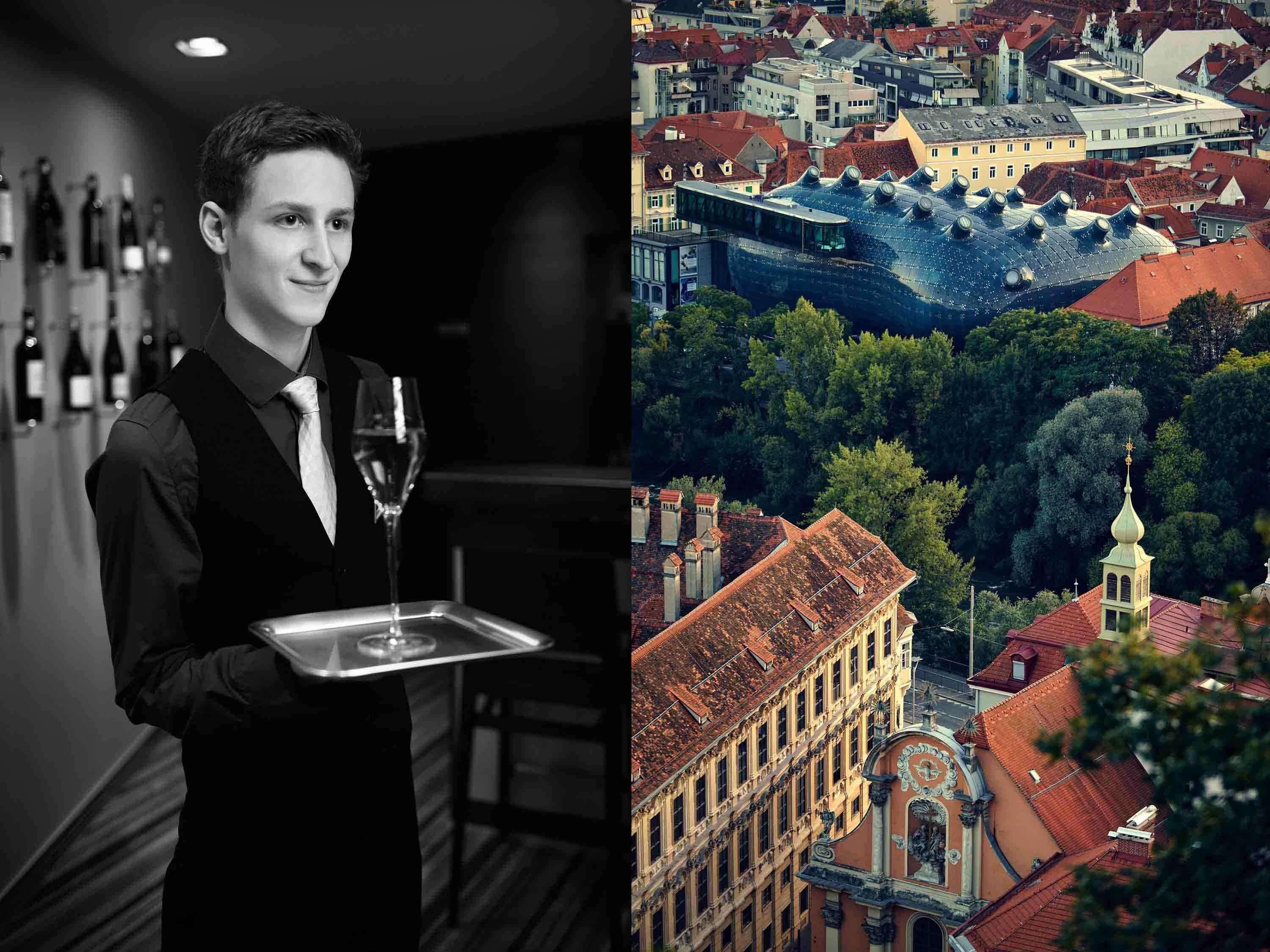 A waiter holding a tray with a glass of wine in a dimly lit room.