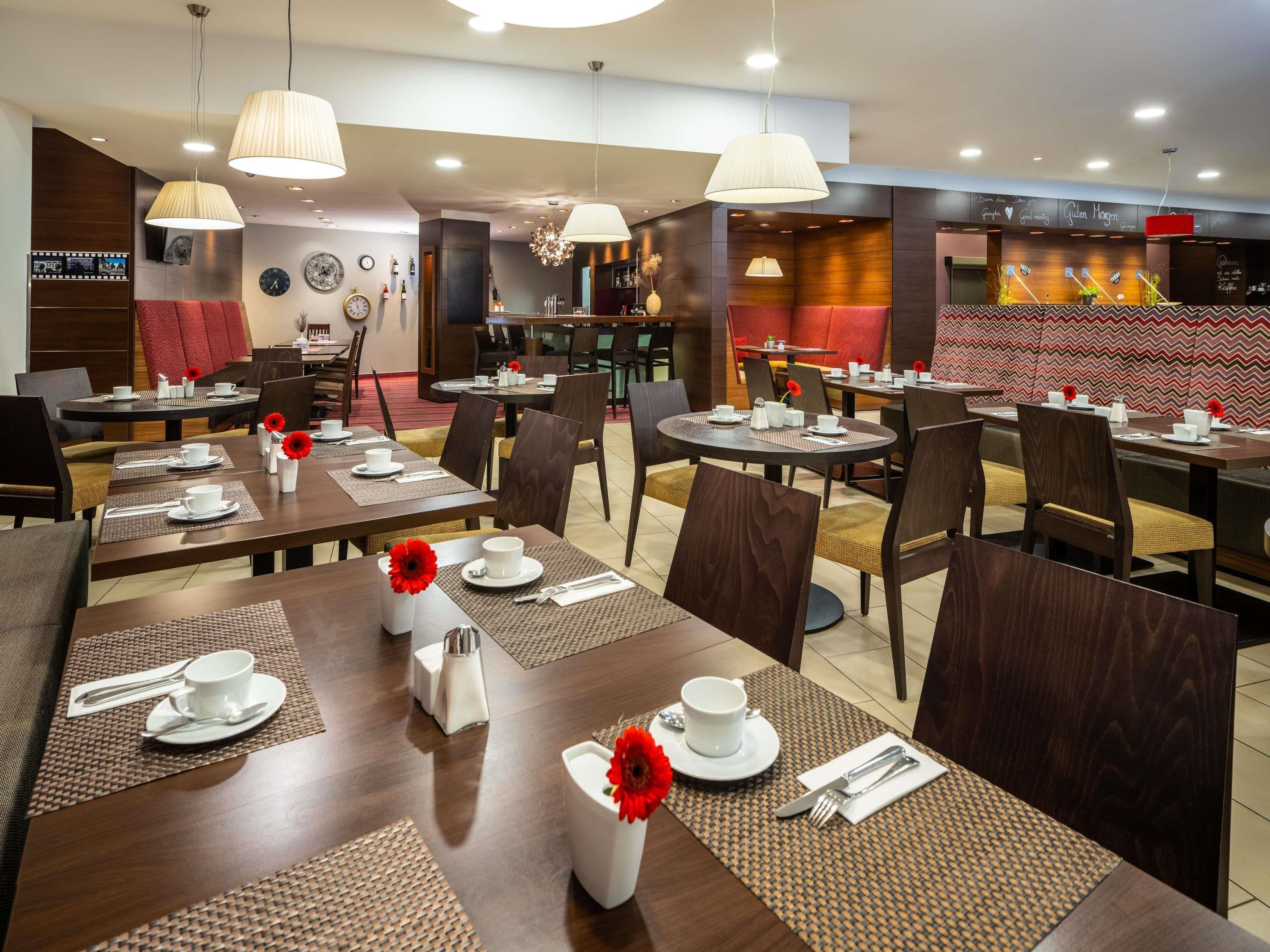 A hotel dining area with multiple tables, chairs, and a bar area.