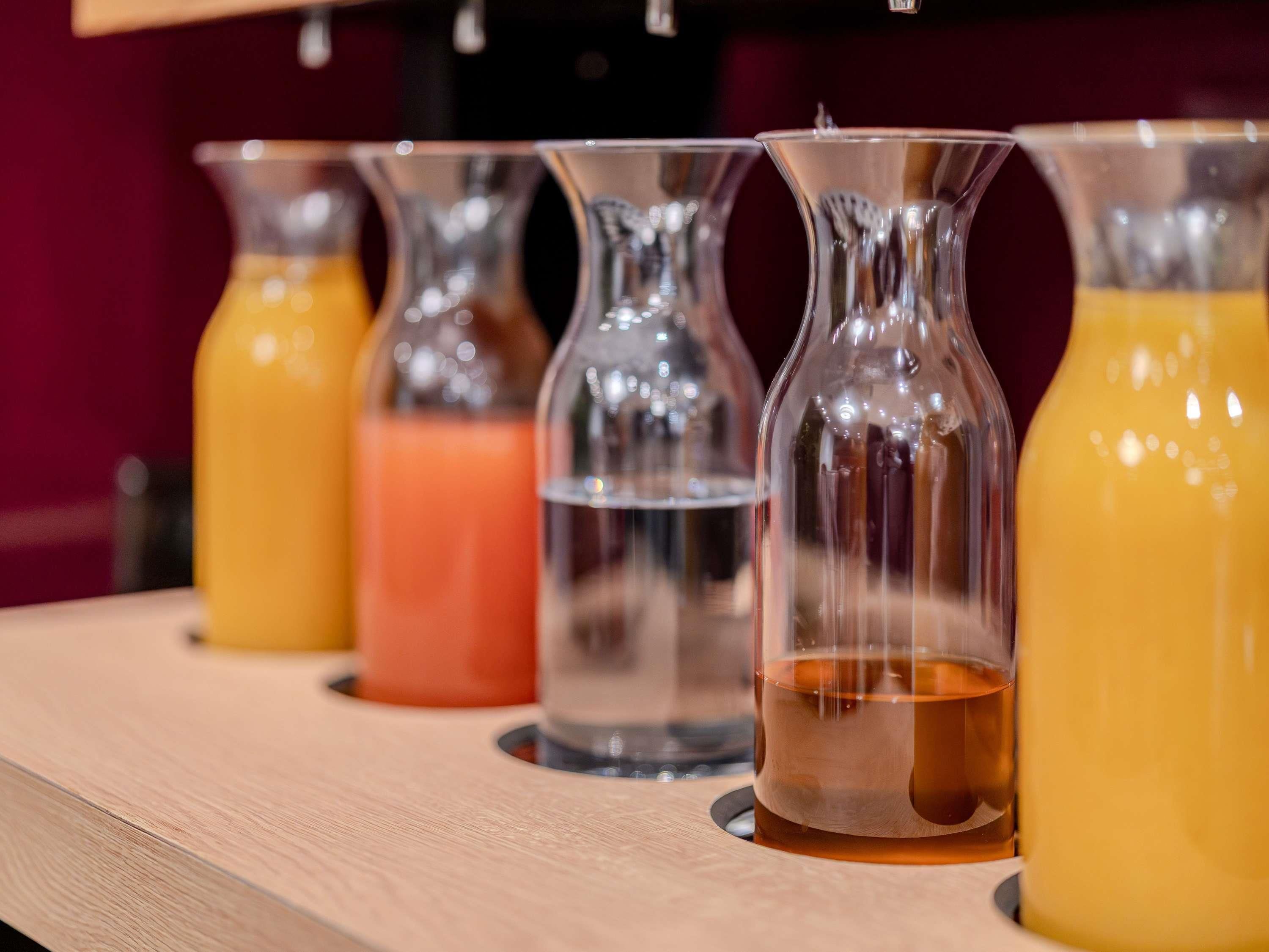 A row of clear glass bottles with different colored liquids on a wooden surface.