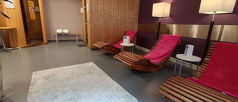 A spa area with wooden loungers, a white rug, and two wall-mounted lamps.