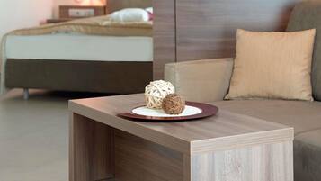 Une chambre d’hôtel moderne comprenant un lit, une table de chevet agrémentée d’objets décoratifs, un canapé et une table de nuit avec une lampe.