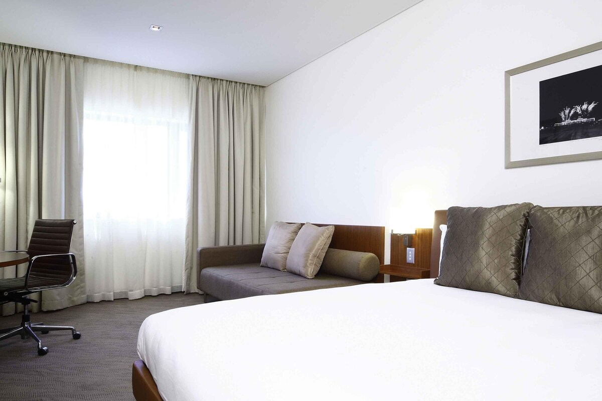 Una habitació d'hotel amb un llit, un sofà, una cadira i un quadre al mur.