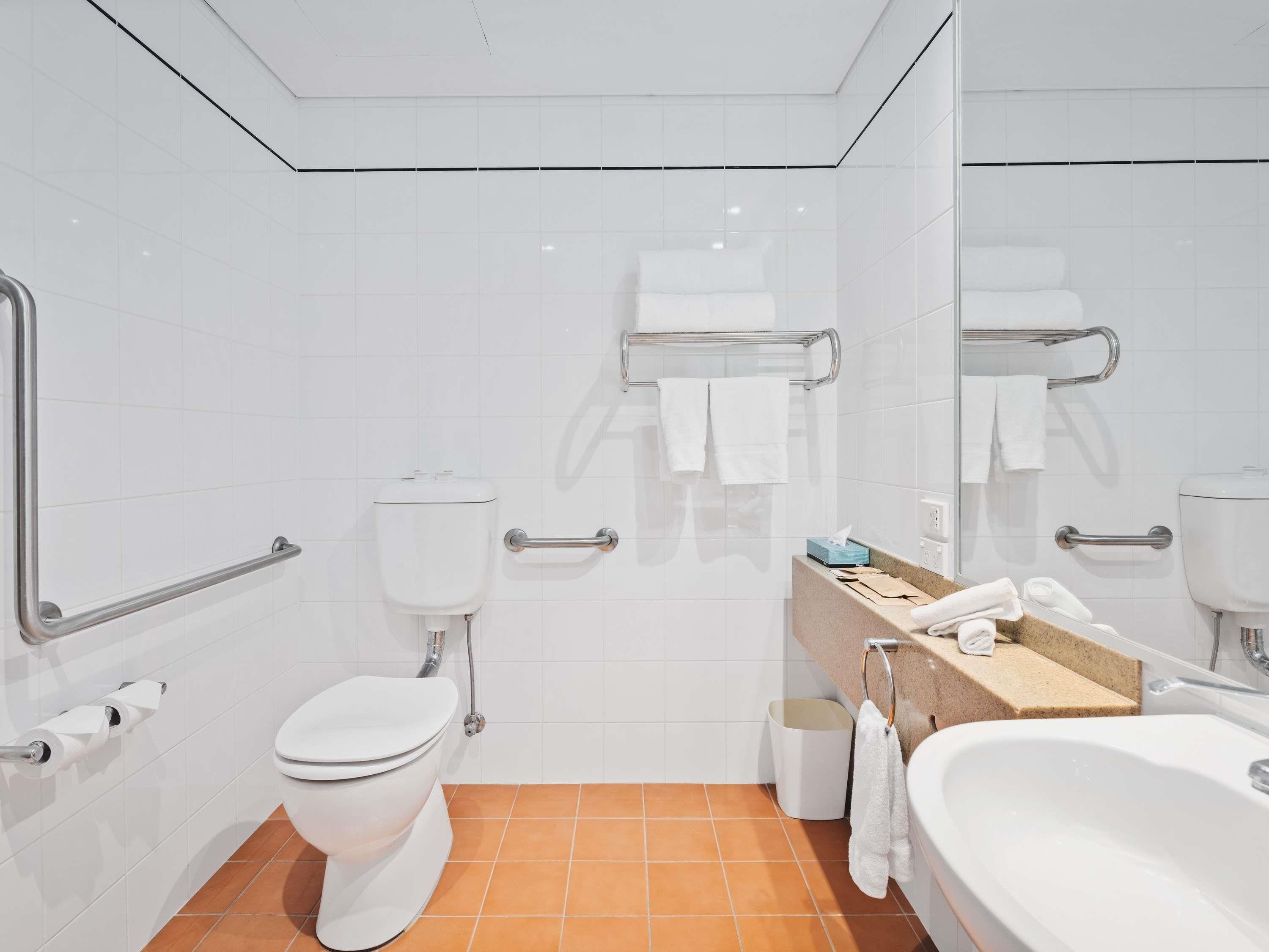 A modern bathroom with a toilet, bidet, sink, and a mirror.