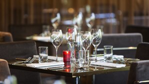 A dining table set with multiple wine glasses, water glasses, and cutlery, with a red candle in the center. - Novotel Canberra (Canberra)