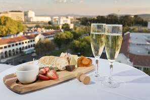 A table with a cheese board, crackers, strawberries, a bottle of wine, and two glasses of wine.