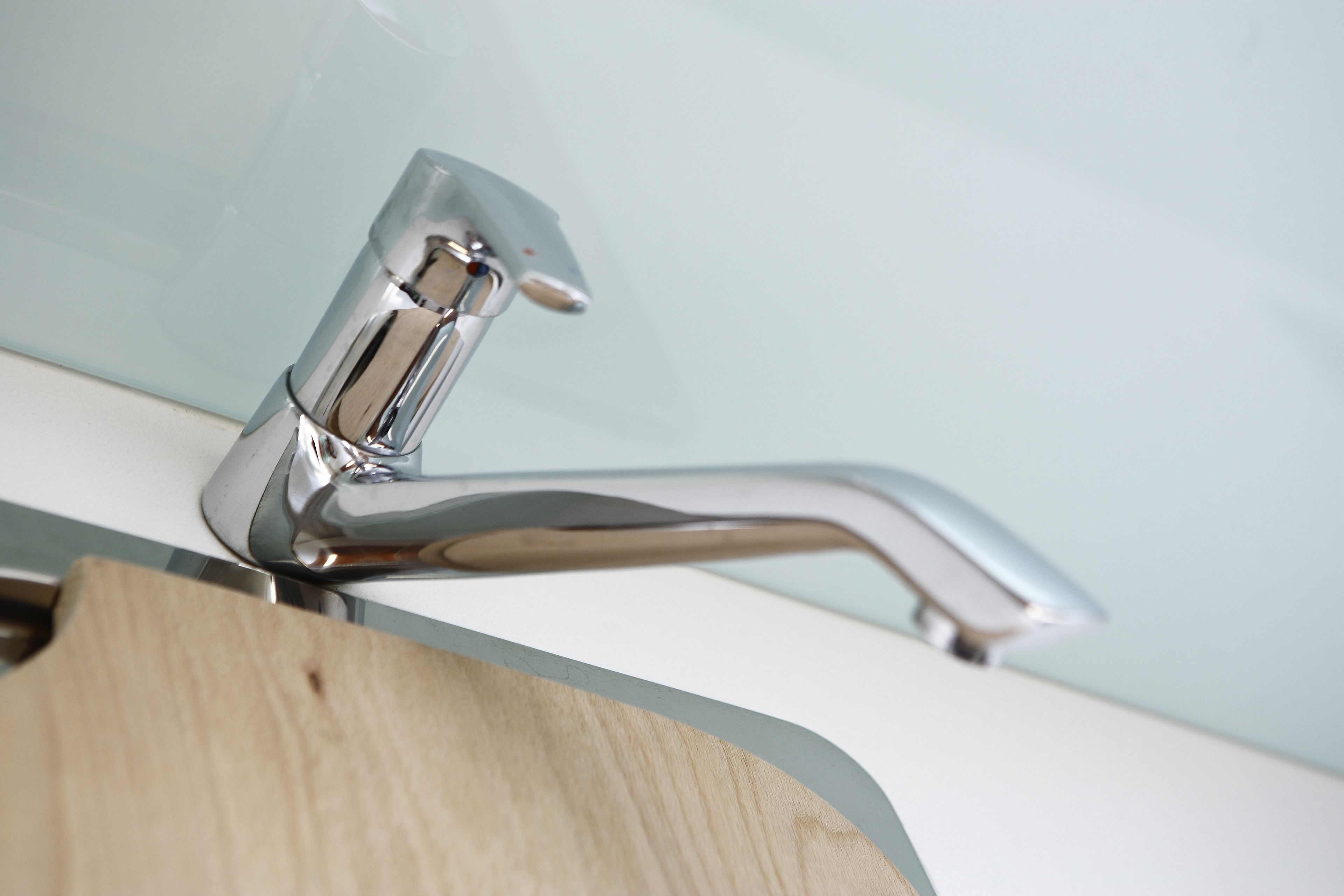 A chrome faucet with a modern design, mounted on a white sink.