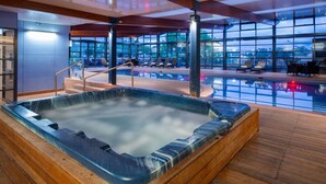 A hot tub in a modern indoor setting with a view of the cityscape through large windows. - Novotel Canberra (Canberra)