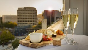 A table with a cheese board, two glasses of white wine, and a bowl of dip. - Novotel Canberra (Canberra)