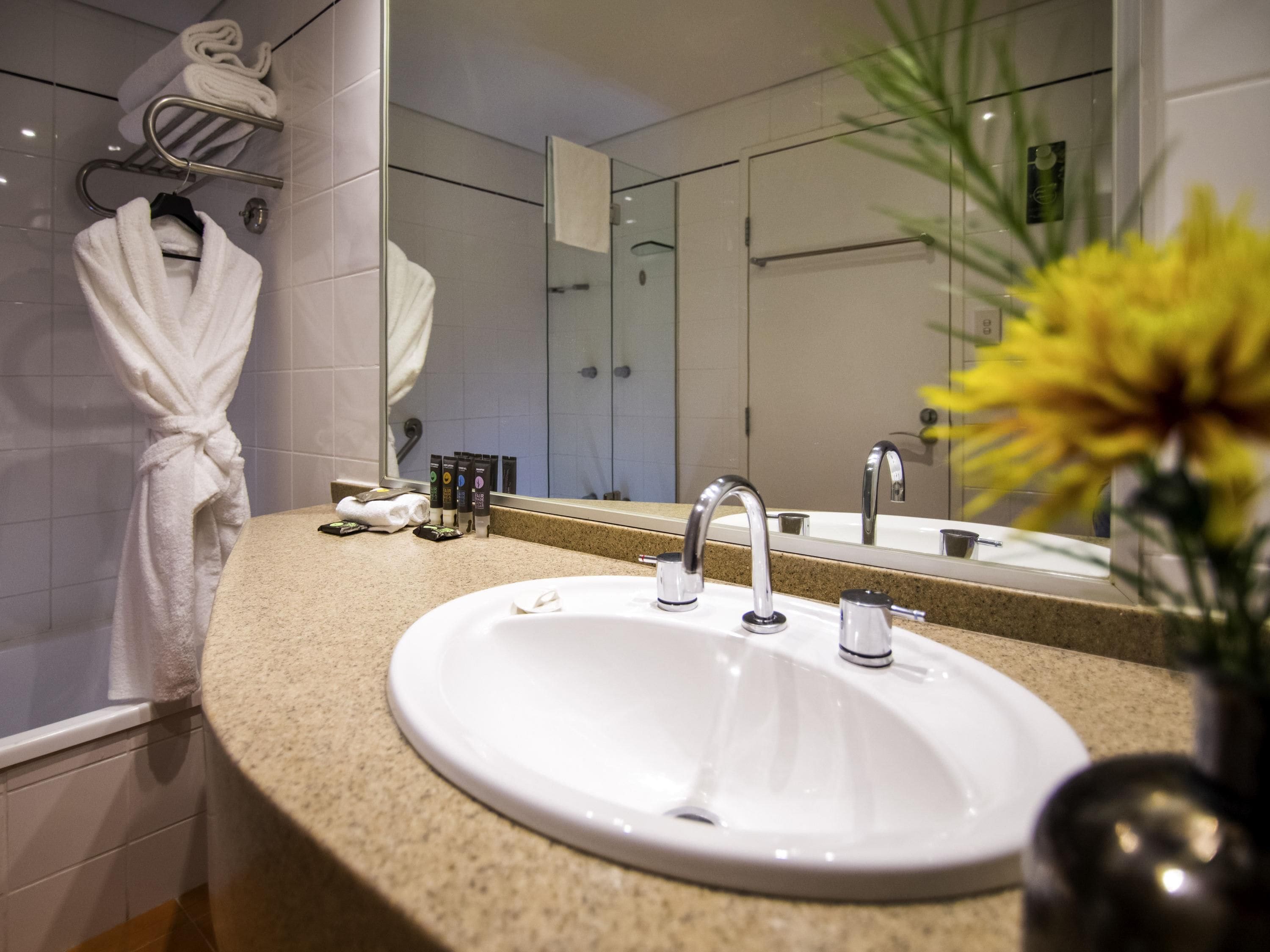 A bathroom with a sink, mirror, and towel rack.