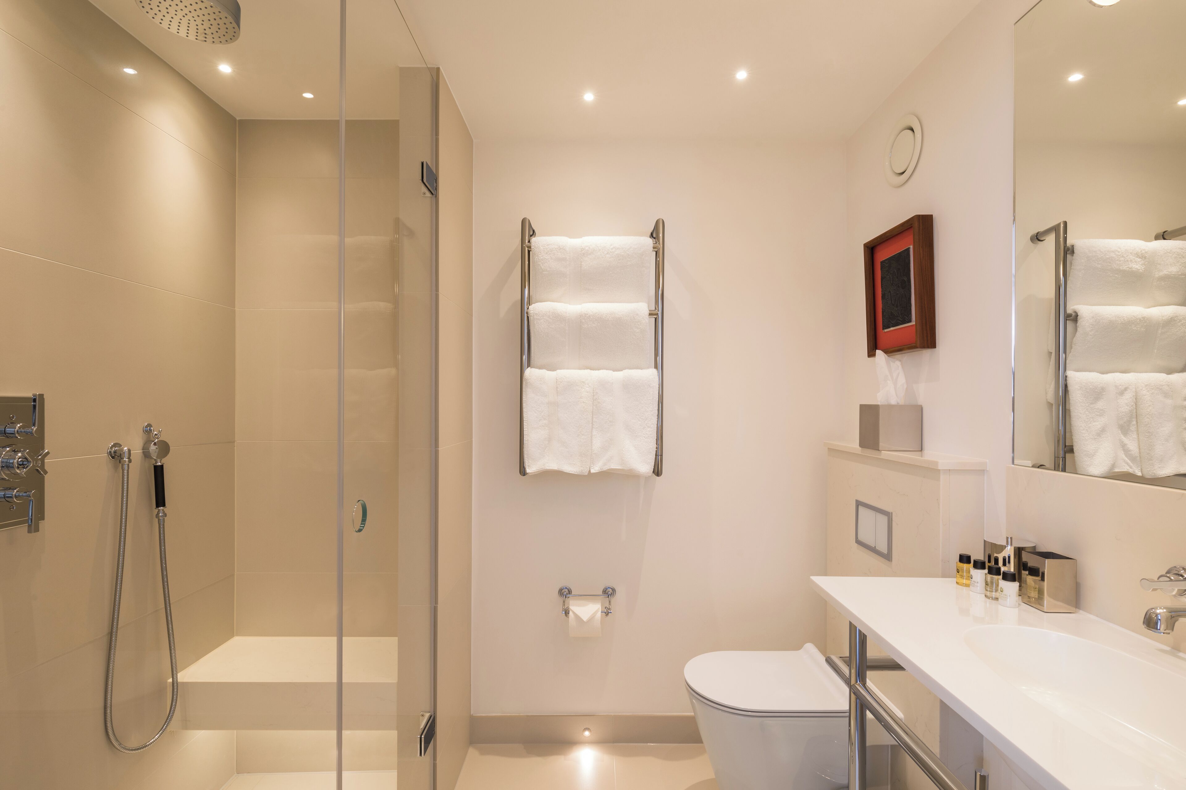 Een moderne badkamer met een douchecabine van glas, een wit toilet en een wastafel met spiegel.