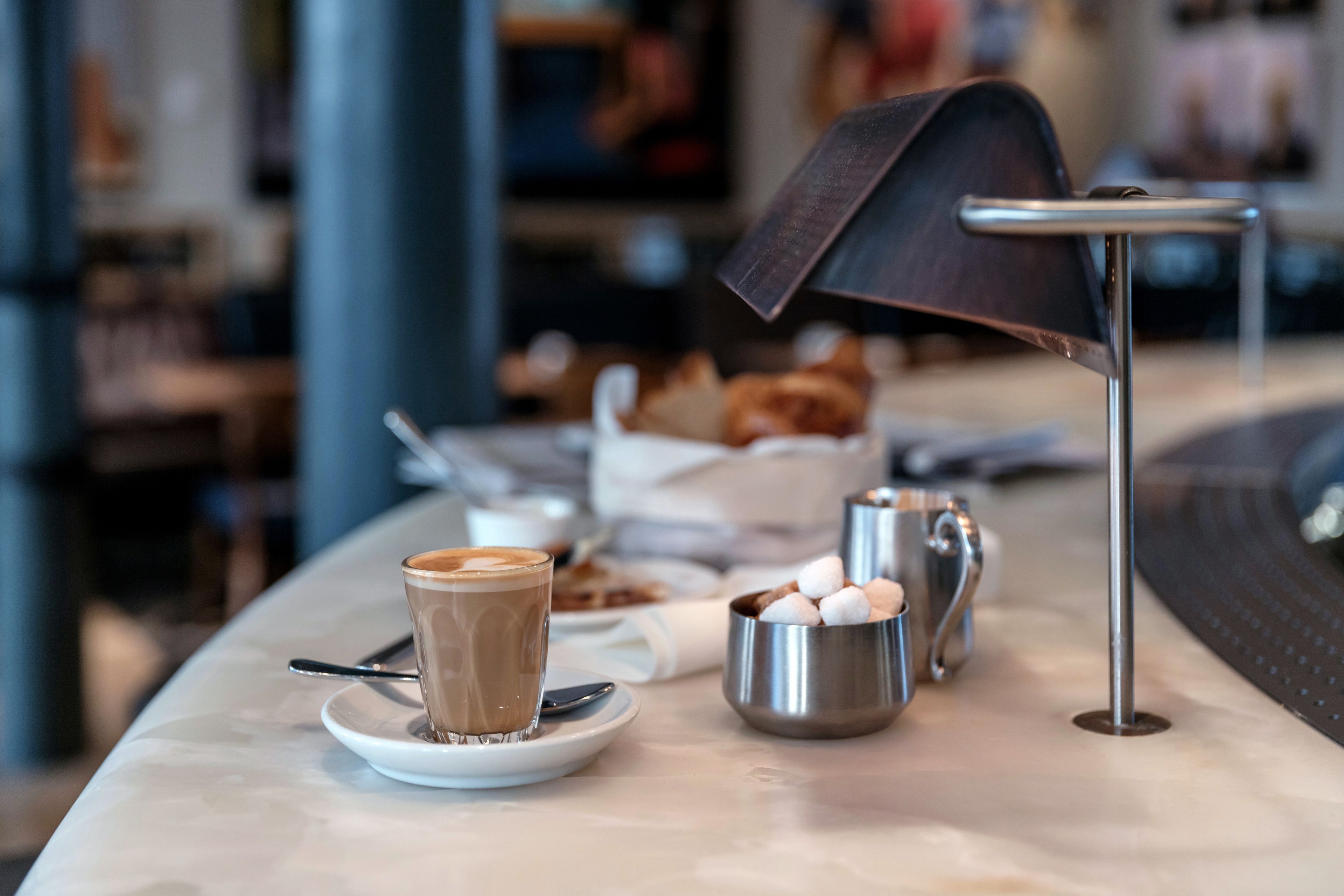 A table with a cup of coffee, a small bowl of marshmallows, and a metal tray.