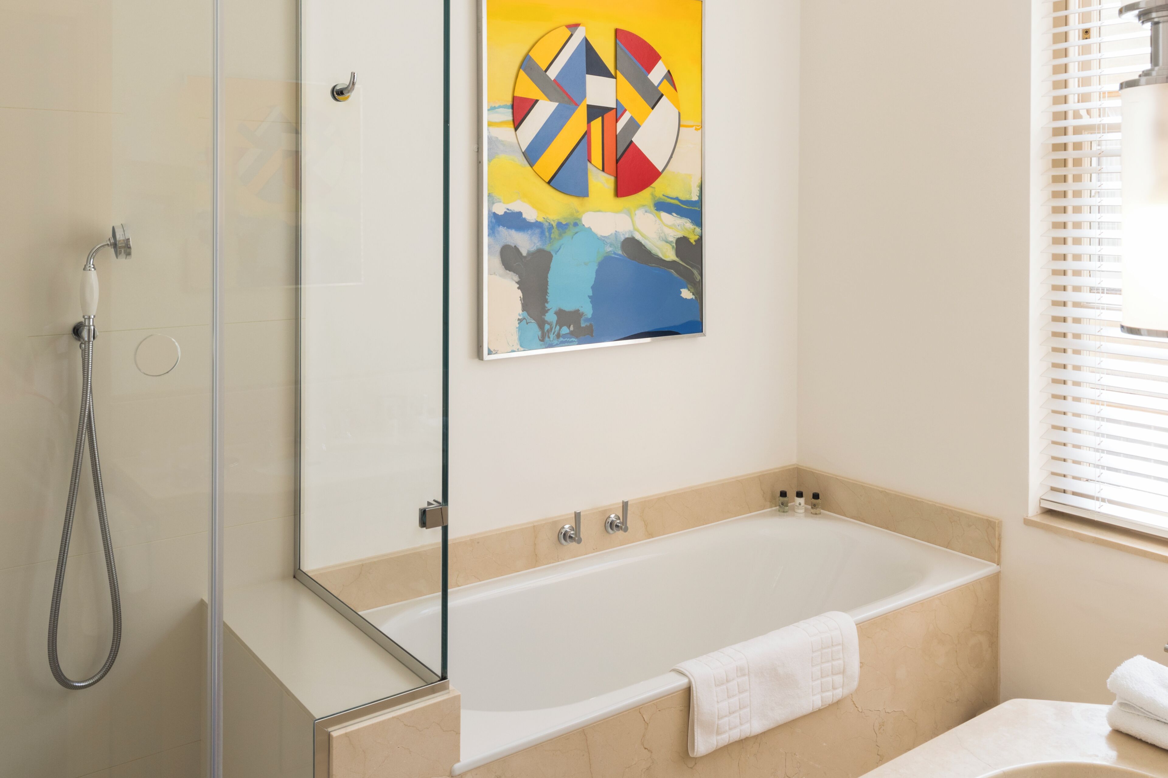 Ein modernes Badezimmer mit Badewanne, Duschkabine aus Glas und einem großen abstrakten Gemälde an der Wand.