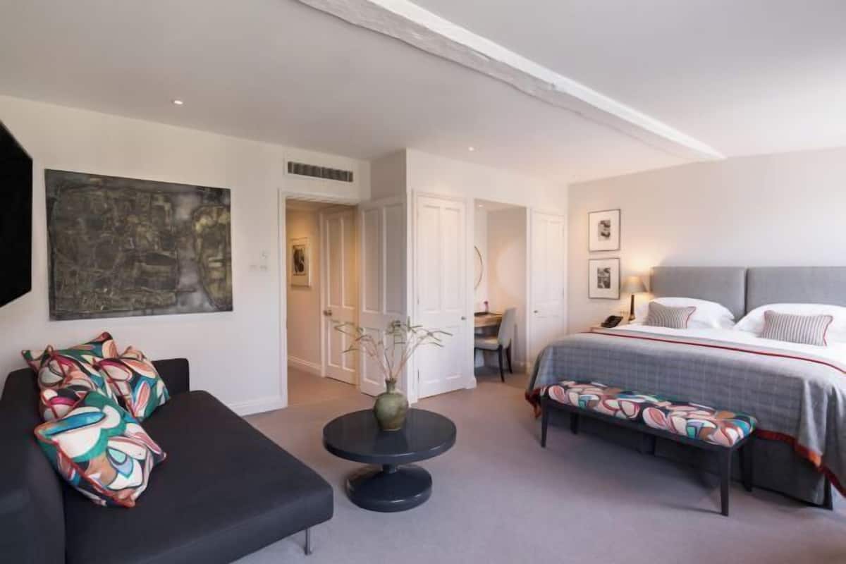 A hotel room with a bed, a sofa, a small round table, and a bench.