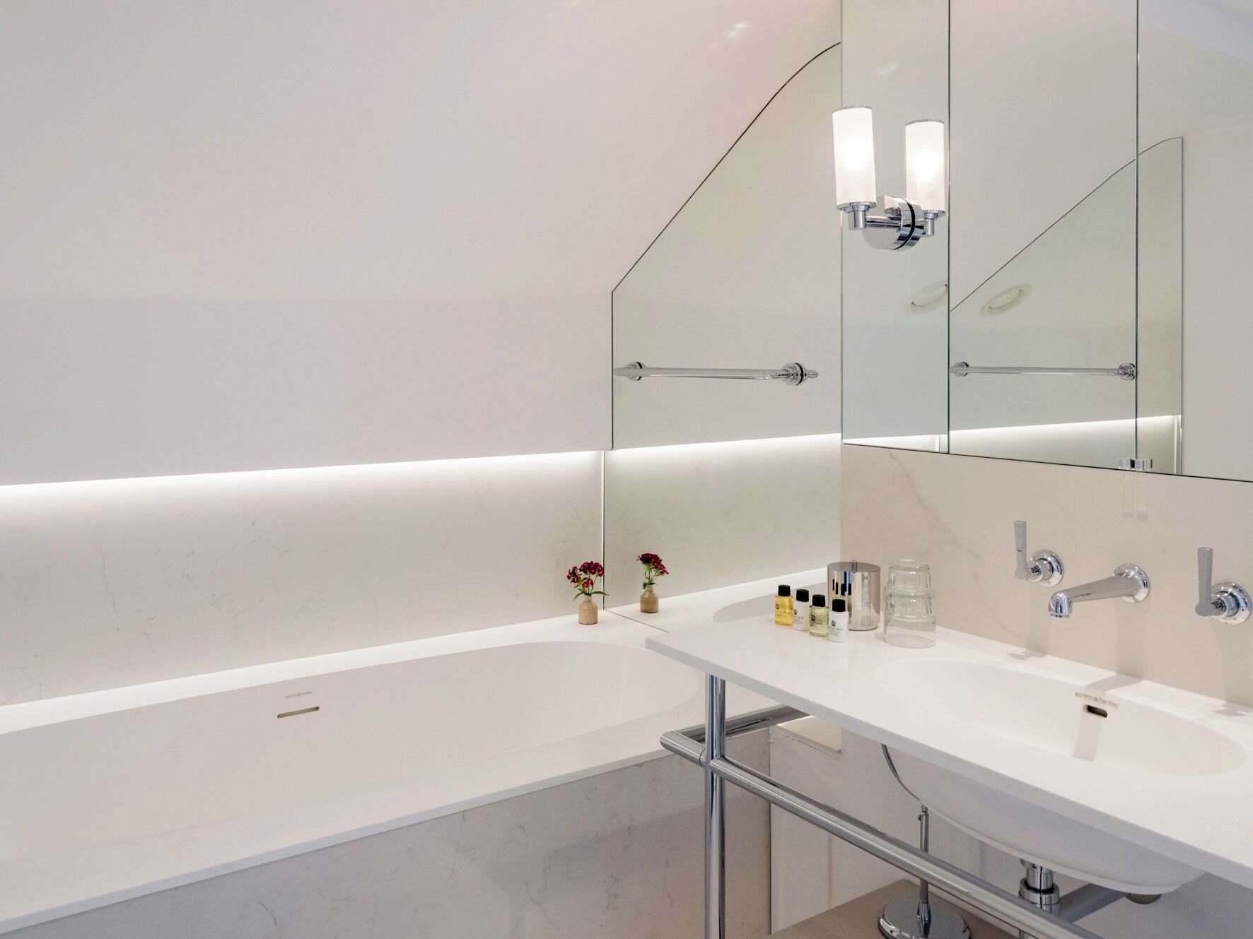 A modern bathroom with a white bathtub, a vanity with a mirror, and a glass shower enclosure.