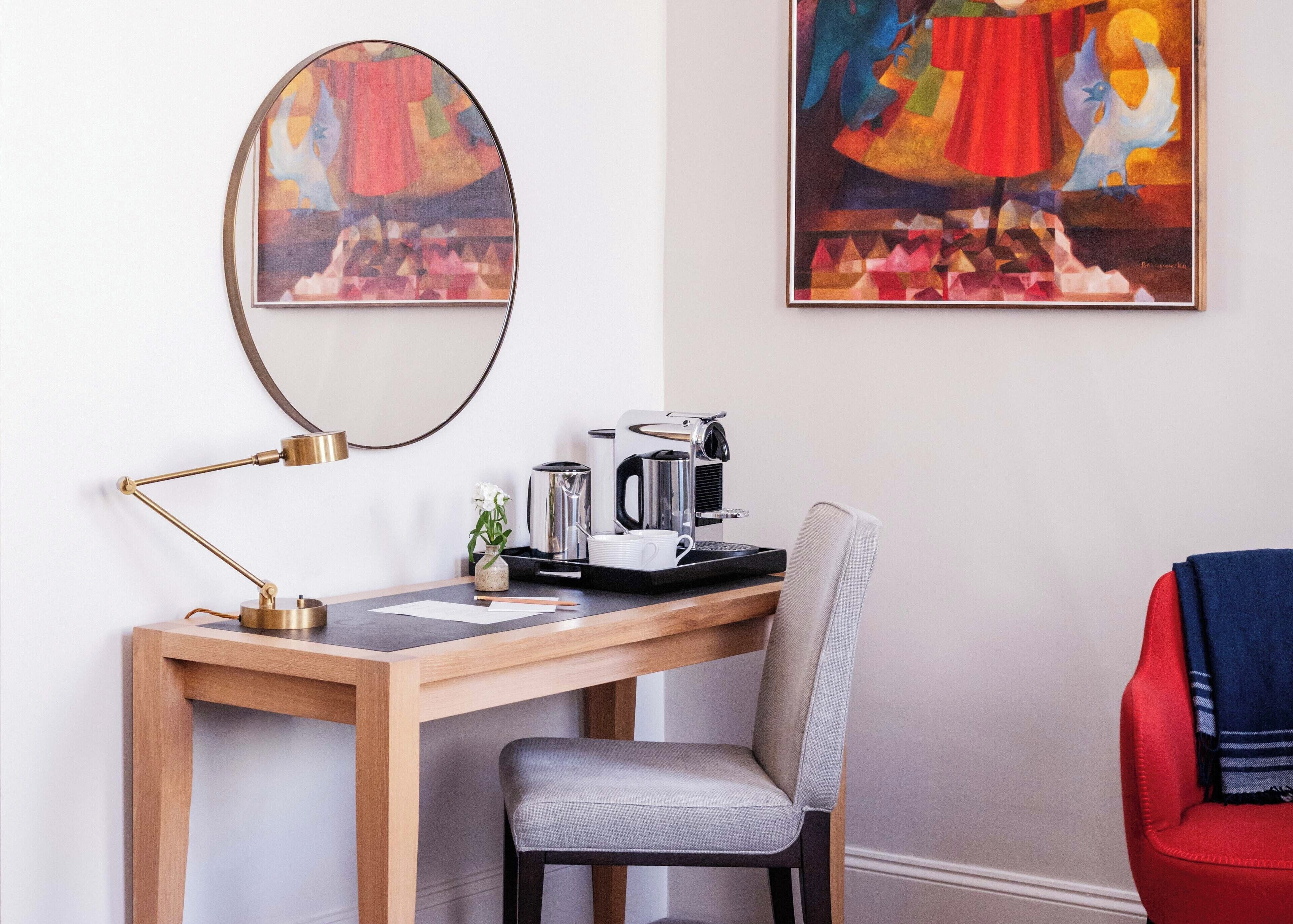 A modern workspace with a wooden desk, a laptop, a coffee maker, and a chair.