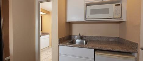 A compact kitchen with a built-in microwave, a sink, and a small countertop.