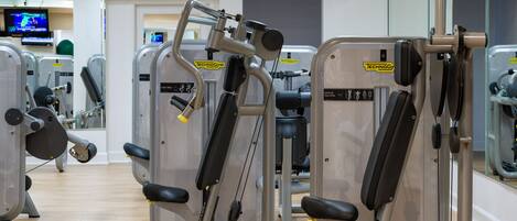A gym with various exercise machines, including a chest press machine and a vertical traction machine.