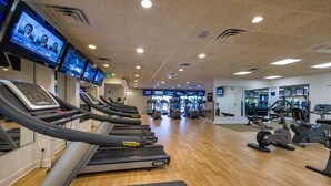 Un gimnasio con cintas de correr, bicicletas estáticas y máquinas de pesas.