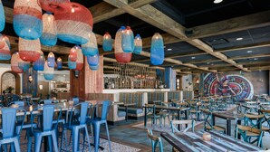 Un restaurante con sillas azules, mesas de madera y faroles azules y rojos colgantes.