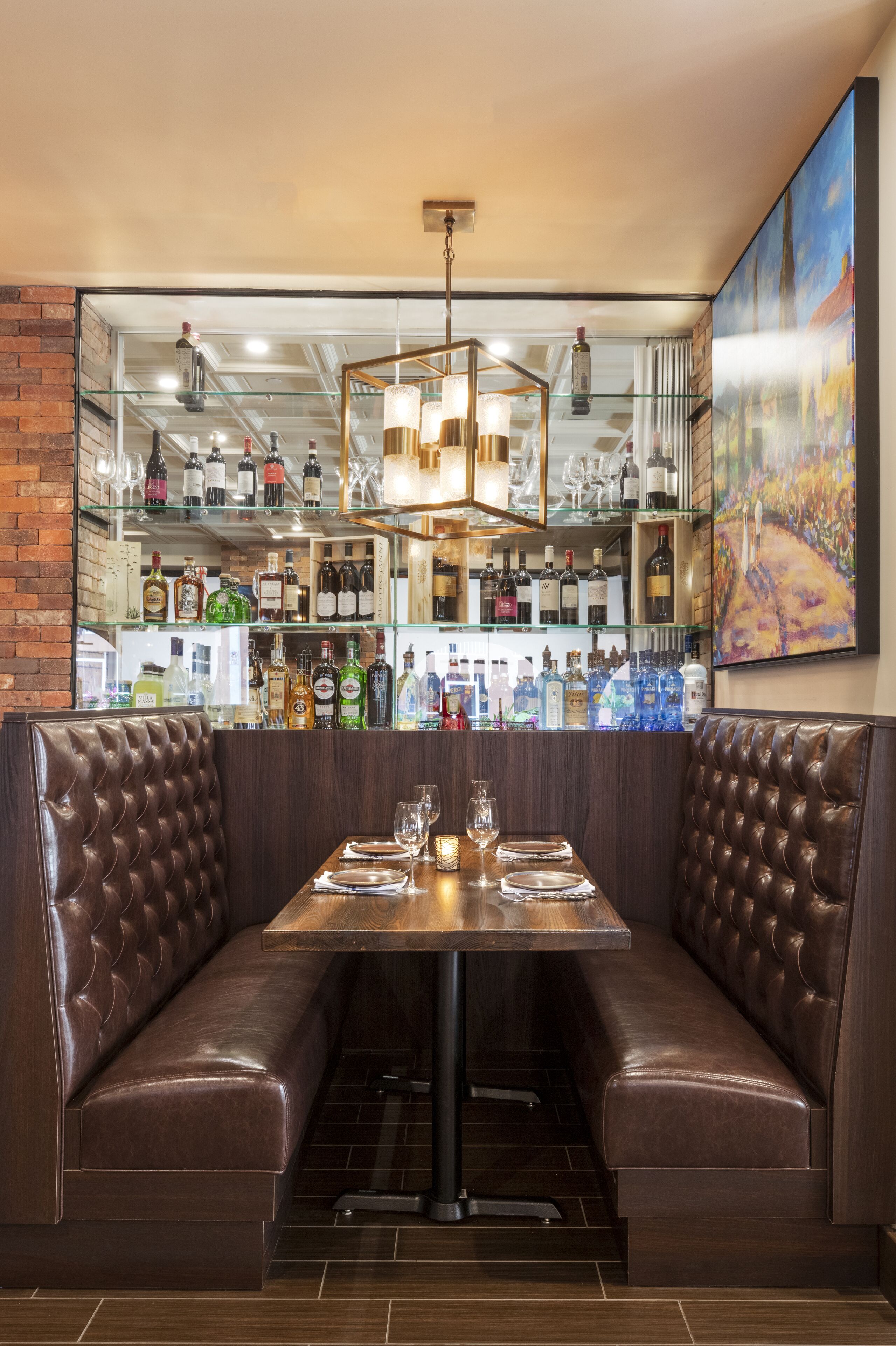 A restaurant with a bar area, leather booth seating, and a variety of bottles on shelves.