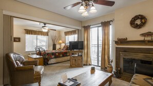A living room with a fireplace, a television, and a ceiling fan. - Carriage House Condominiums by All Seasons Resort (Park City)
