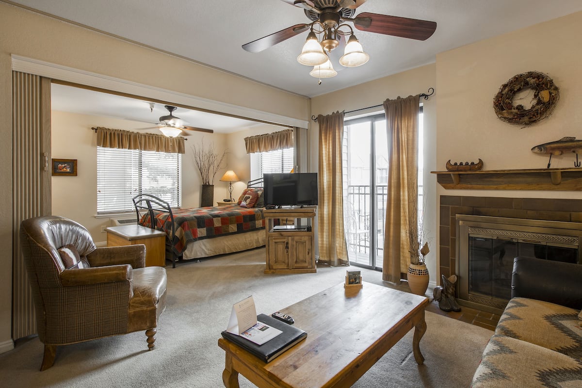 A living room with a fireplace, a television, and a ceiling fan.