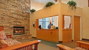 A lobby with a stone fireplace, wooden reception desk, and seating area. - Carriage House Condominiums by All Seasons Resort (Park City)