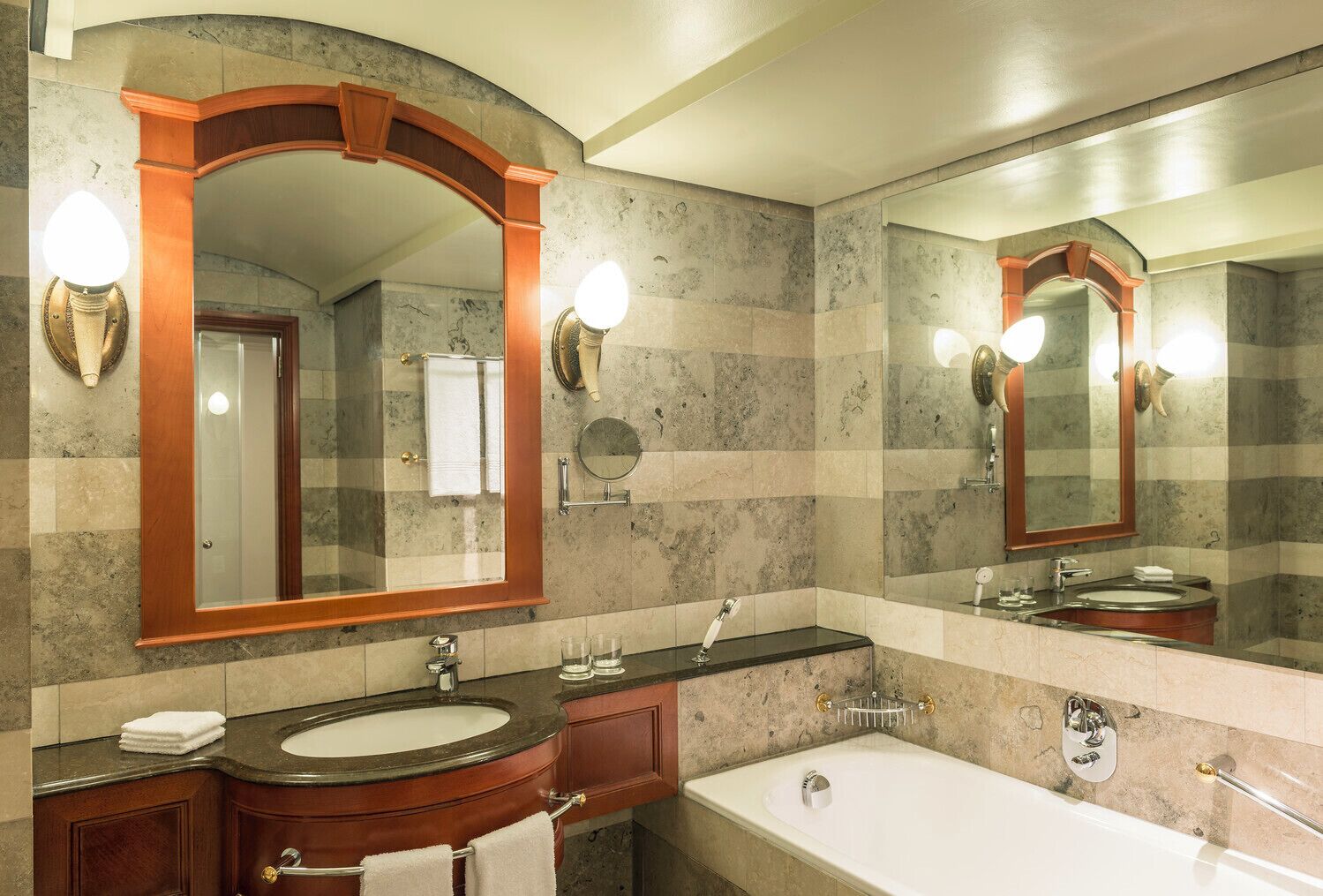 Un bany amb un mirall gran, un lavabo, una banyera i un moble de tocador amb un suport per a tovalloles.