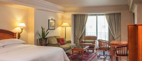 Una habitación de hotel con una cama, un sofá, una silla, una mesa y un escritorio.