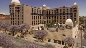 Un hotel grande con varios pisos, un patio central con asientos y una estructura en forma de cúpula.