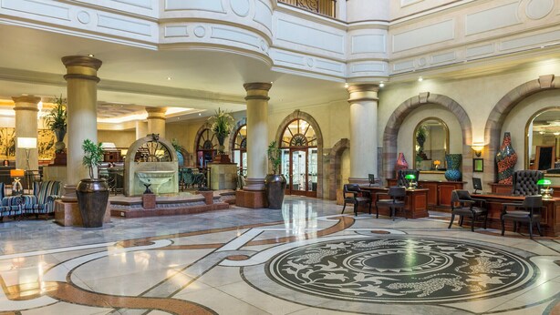 Un vestíbulo amplio con un diseño de piso central ornamentado, varias zonas de descanso y un mostrador de recepción.