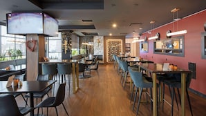 A modern restaurant interior with high tables and chairs, a bar area, and a view through large windows. - Best Western Premier Aberdeen Kamloops (Kamloops)