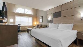 A hotel room with a large bed, a desk, a chair, and a window with a view.